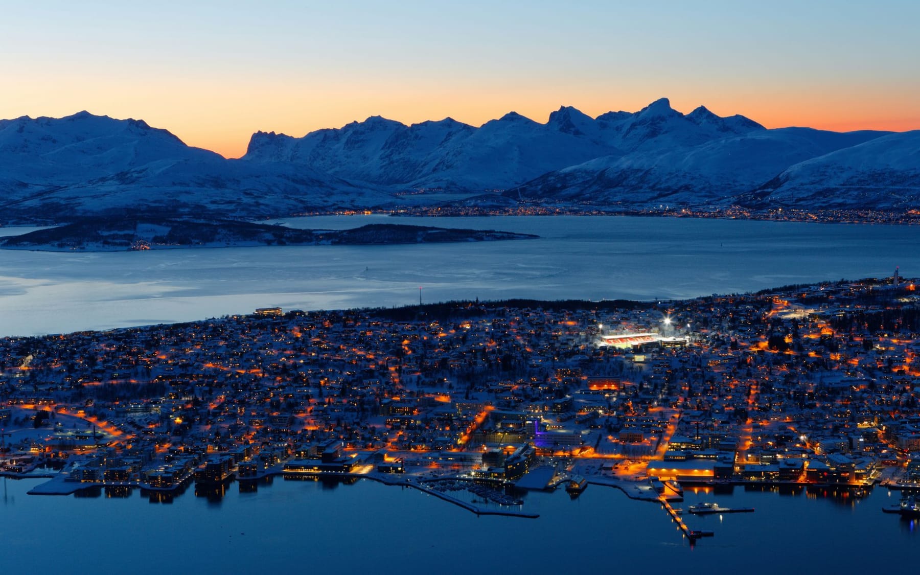 Akşam ışıklarıyla Tromsø ve karlı dağlar